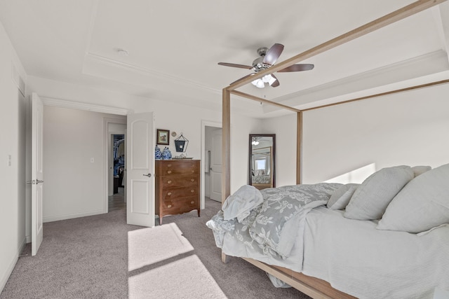 bedroom with a raised ceiling, light colored carpet, and ceiling fan