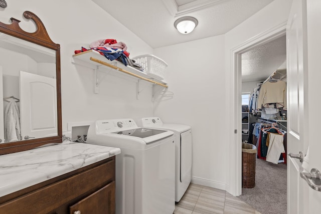 clothes washing area featuring light carpet, washing machine and dryer, and a textured ceiling