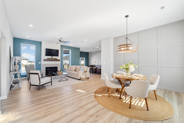 dining area featuring ceiling fan, light hardwood / wood-style floors, and a fireplace