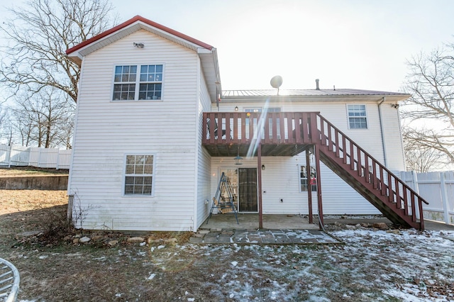 snow covered back of property with a patio