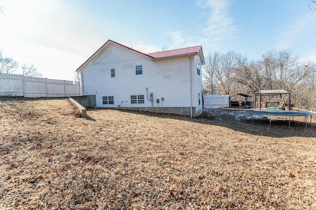 rear view of house with a lawn and a trampoline