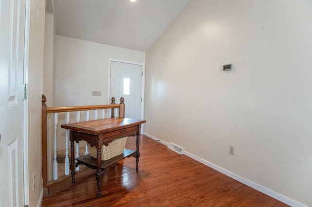 corridor featuring hardwood / wood-style floors and vaulted ceiling