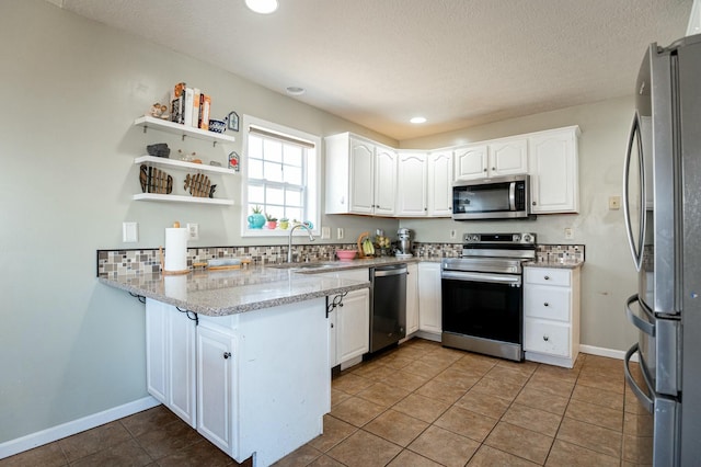 kitchen featuring appliances with stainless steel finishes, white cabinetry, sink, kitchen peninsula, and tile patterned floors