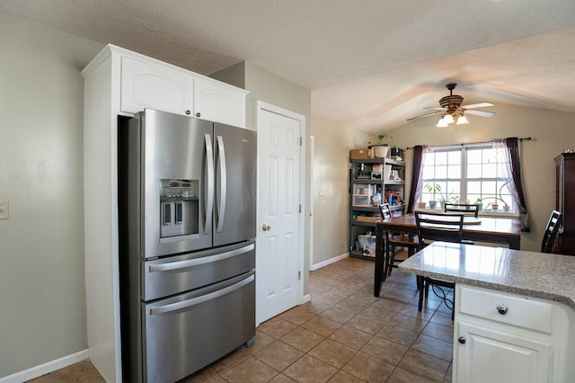 kitchen featuring white cabinets, vaulted ceiling, stainless steel fridge, and tile patterned floors