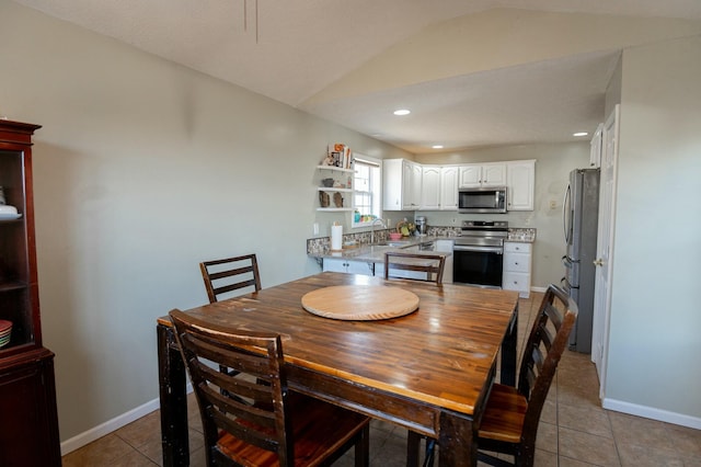 tiled dining area featuring sink and lofted ceiling