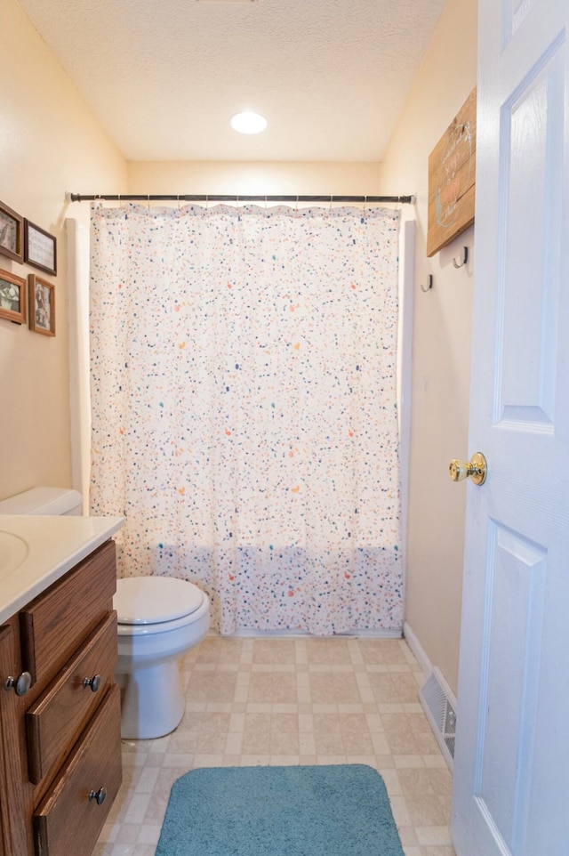 bathroom featuring toilet, vanity, and walk in shower