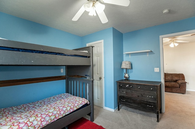 bedroom featuring ceiling fan, light colored carpet, and a textured ceiling