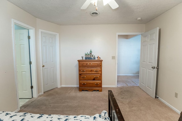 bedroom featuring light carpet, a textured ceiling, and ceiling fan