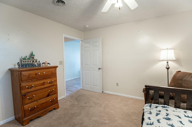 bedroom featuring a textured ceiling, light colored carpet, and ceiling fan