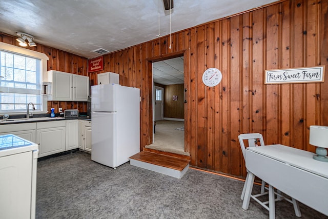 kitchen with range, wooden walls, sink, white cabinets, and white refrigerator