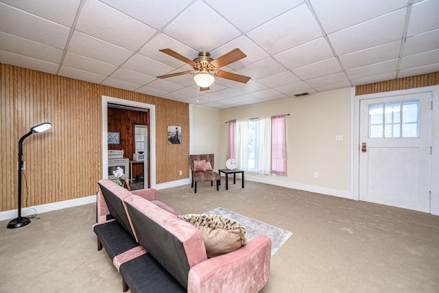 living room featuring wood walls, carpet flooring, and ceiling fan