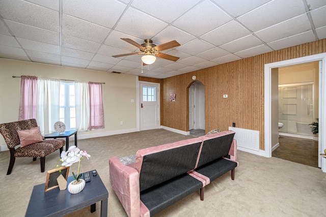 living room featuring ceiling fan, carpet flooring, and wooden walls