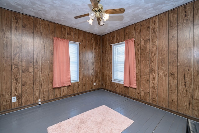 unfurnished room featuring a textured ceiling, wooden walls, and dark hardwood / wood-style flooring