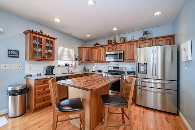 kitchen with wooden counters, sink, a center island, light hardwood / wood-style floors, and stainless steel appliances