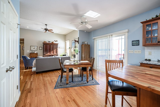 dining space featuring ceiling fan, vaulted ceiling, light hardwood / wood-style floors, and a textured ceiling