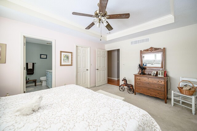 carpeted bedroom featuring crown molding, connected bathroom, ceiling fan, and a raised ceiling