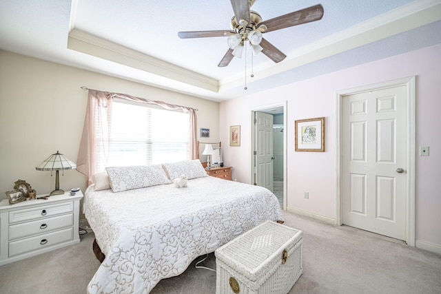 carpeted bedroom featuring ceiling fan, ensuite bath, and a raised ceiling