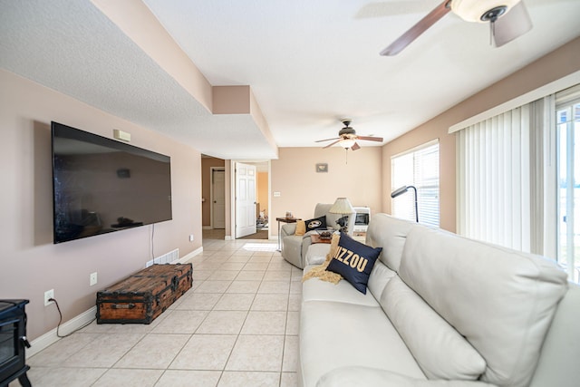 tiled living room featuring a wood stove and ceiling fan