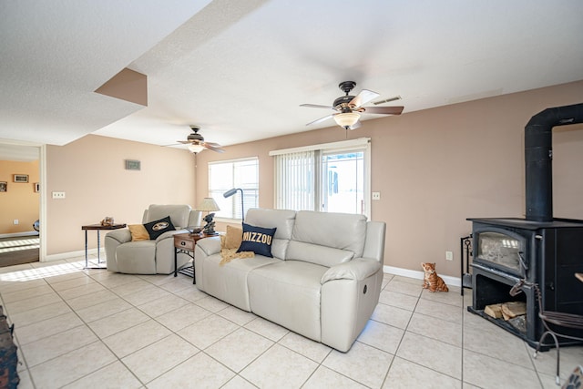 tiled living room with ceiling fan and a wood stove