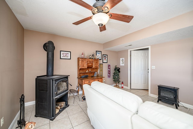 tiled living room featuring ceiling fan, a textured ceiling, and a wood stove