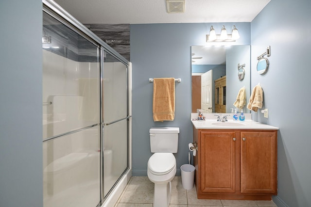 bathroom with tile patterned floors, a shower with door, toilet, and vanity