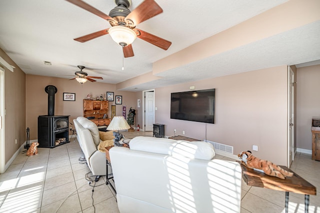 tiled living room featuring ceiling fan and a wood stove