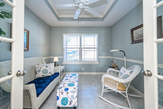 sitting room with ornamental molding, ceiling fan, and a raised ceiling