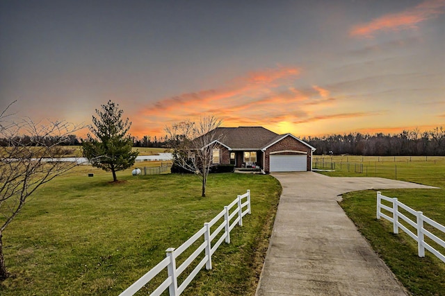 ranch-style house with a lawn, a garage, and a rural view