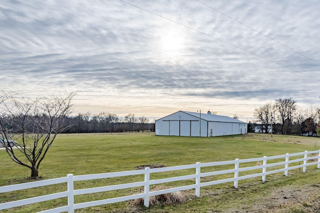 yard at dusk featuring an outbuilding and a rural view