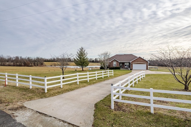 view of front facade featuring a garage, a rural view, and a front yard