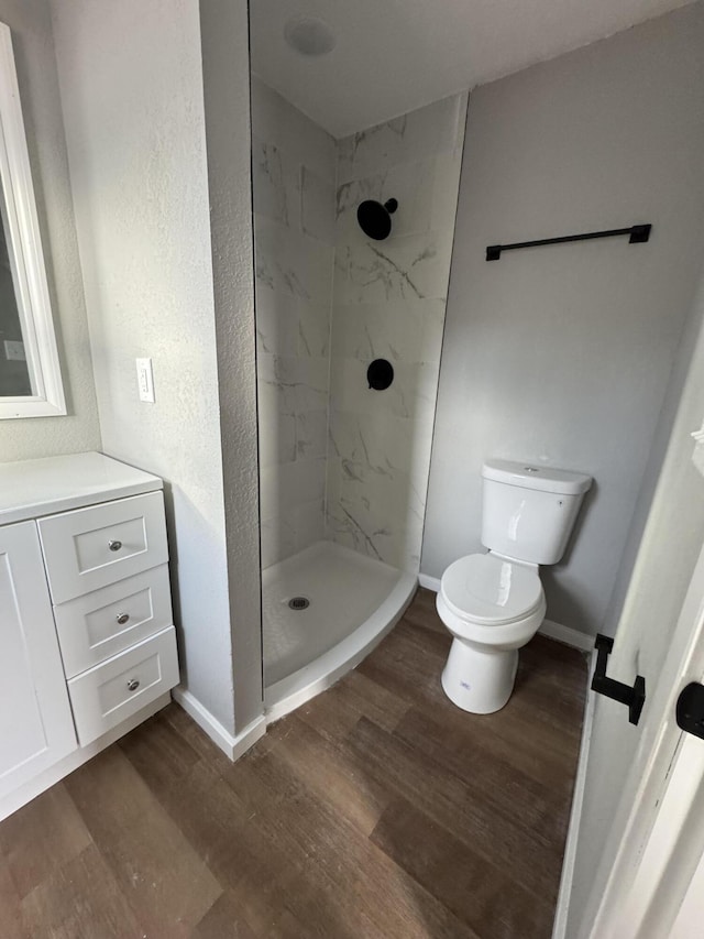 bathroom featuring vanity, toilet, hardwood / wood-style floors, and a tile shower