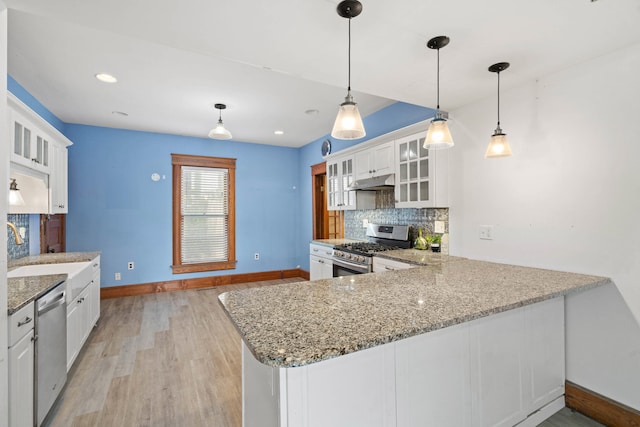 kitchen with white cabinetry, backsplash, hanging light fixtures, kitchen peninsula, and stainless steel appliances