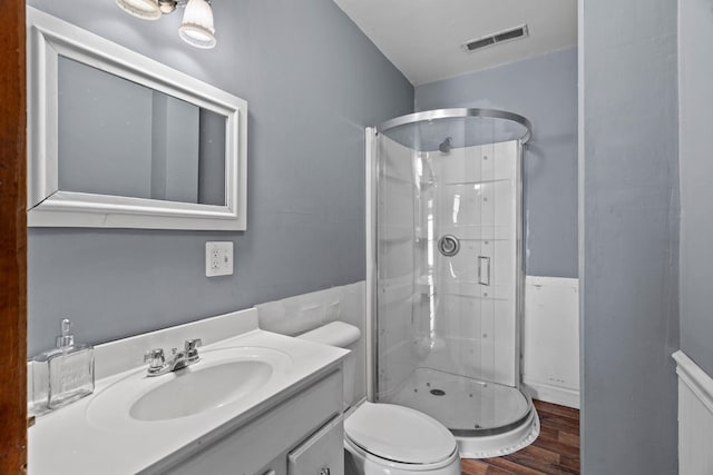 bathroom featuring vanity, hardwood / wood-style floors, a shower with door, and toilet