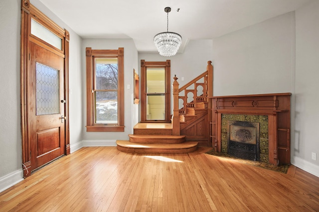 interior space with an inviting chandelier, a fireplace, and light hardwood / wood-style floors