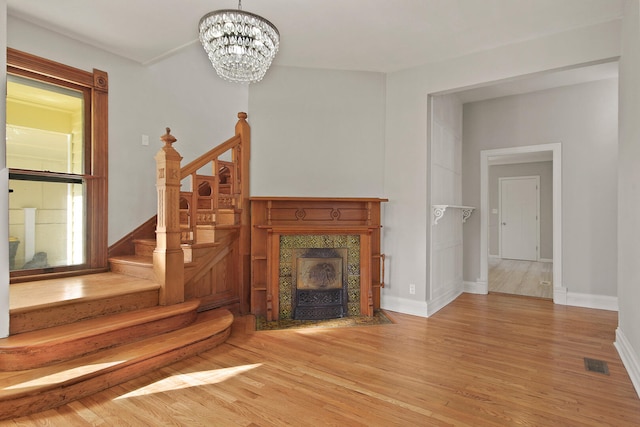 unfurnished living room with an inviting chandelier, a fireplace, and wood-type flooring