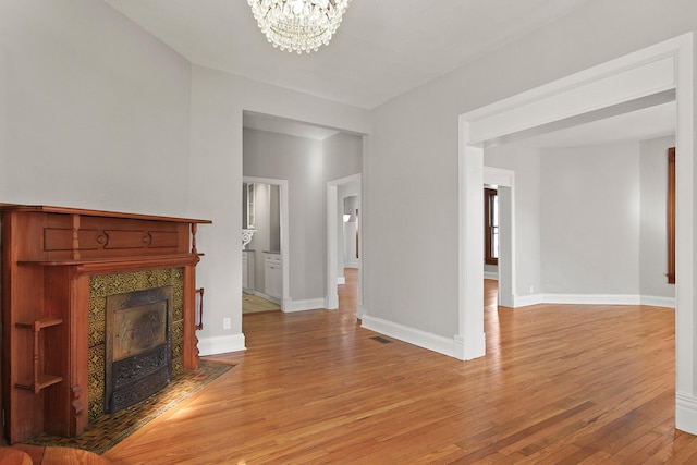 unfurnished living room with light hardwood / wood-style flooring, a fireplace, and an inviting chandelier