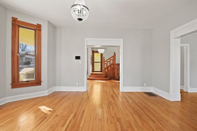 empty room with a chandelier and light hardwood / wood-style flooring