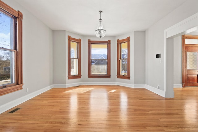 empty room with a chandelier and light hardwood / wood-style floors