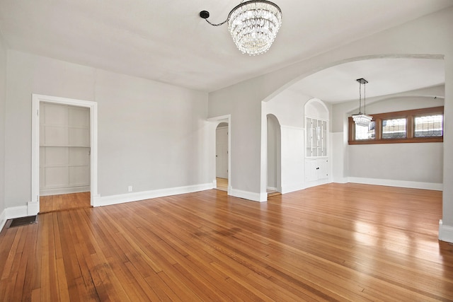 spare room with hardwood / wood-style floors and a chandelier