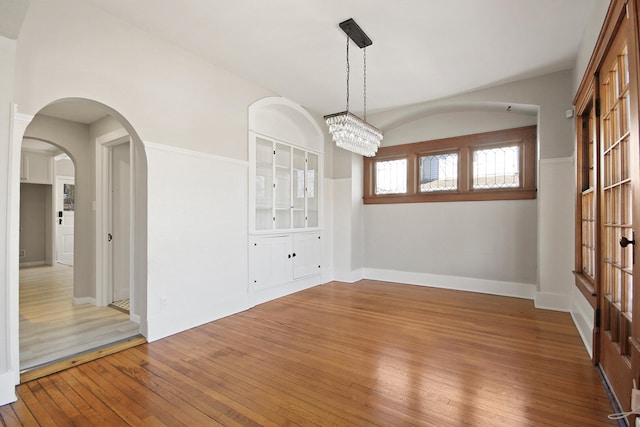 unfurnished dining area featuring wood-type flooring and a notable chandelier