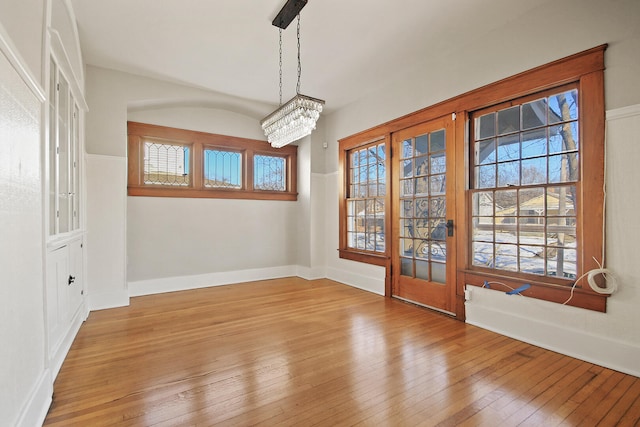 unfurnished dining area featuring plenty of natural light, a chandelier, and light hardwood / wood-style flooring