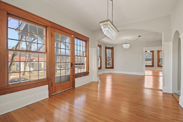 unfurnished dining area featuring an inviting chandelier and light hardwood / wood-style flooring