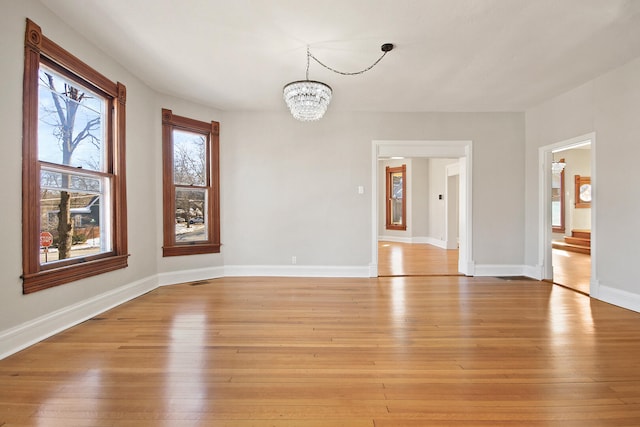 unfurnished room with light hardwood / wood-style floors and a chandelier