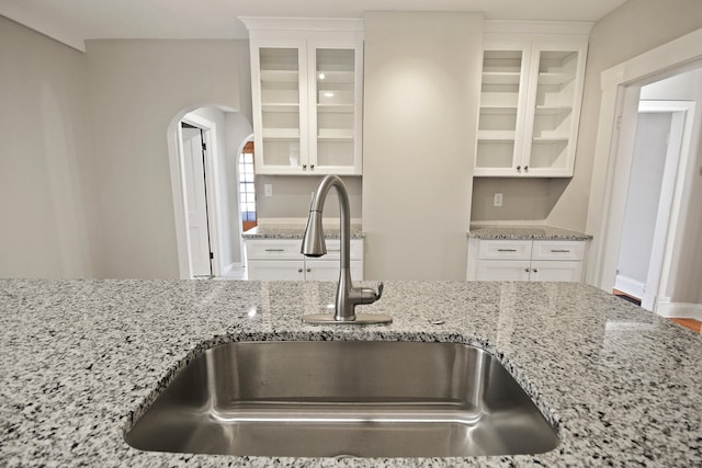 kitchen featuring white cabinetry, sink, and light stone countertops