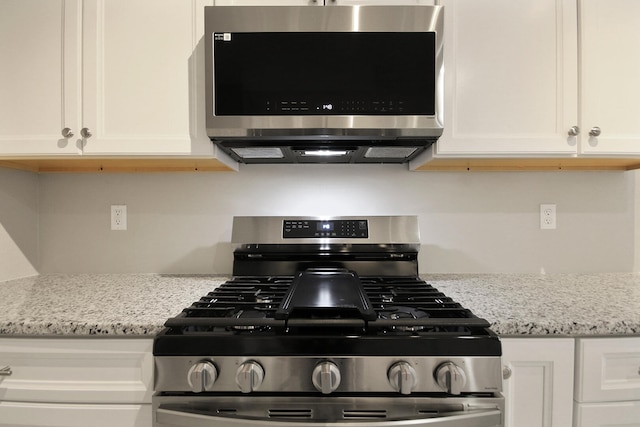 kitchen with white cabinetry, appliances with stainless steel finishes, and light stone countertops