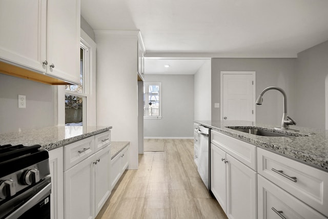 kitchen with light stone counters, sink, and white cabinets