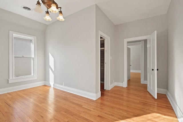 spare room featuring a chandelier and light hardwood / wood-style flooring