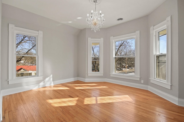 unfurnished dining area featuring an inviting chandelier and light hardwood / wood-style floors