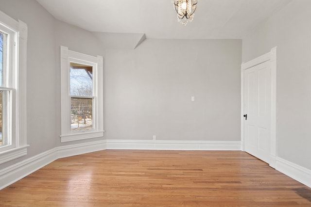 empty room featuring a notable chandelier and light hardwood / wood-style flooring