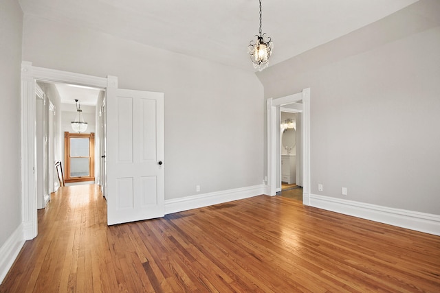 unfurnished room with hardwood / wood-style floors and a notable chandelier